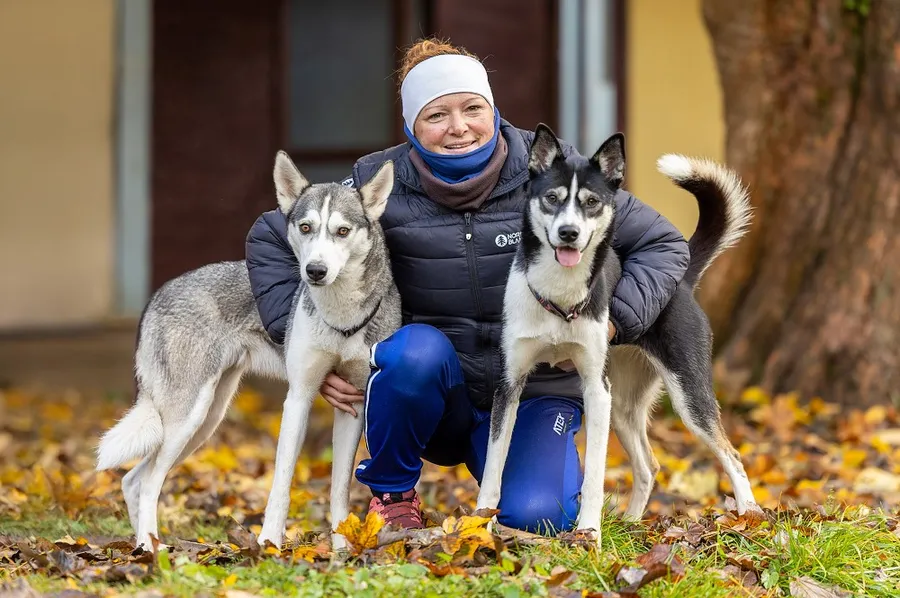 Žena se dvěma husky při podzimním fotografování