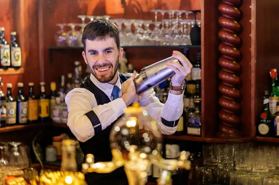Barman při přípravě nápoje za barem