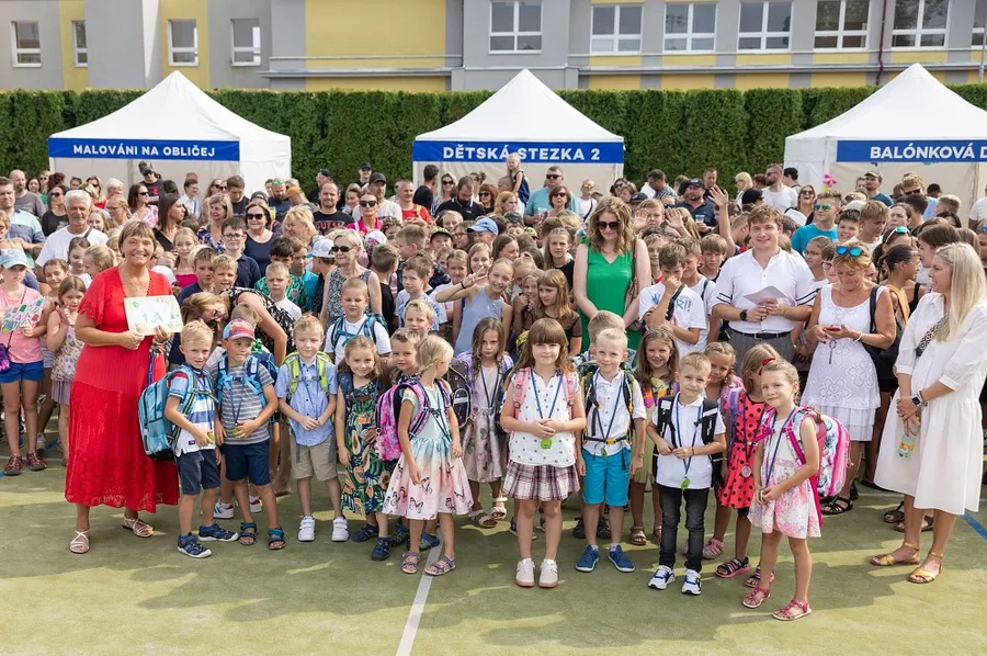 Velká skupina dětí a učitelů před školou